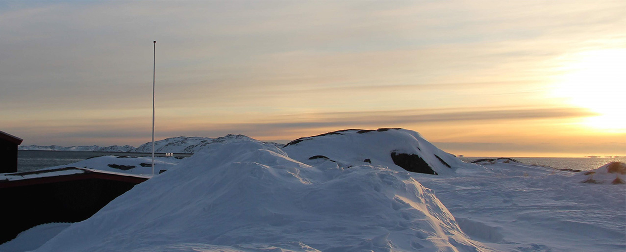 Billedet viser solnedgang over snedrive og bygning 