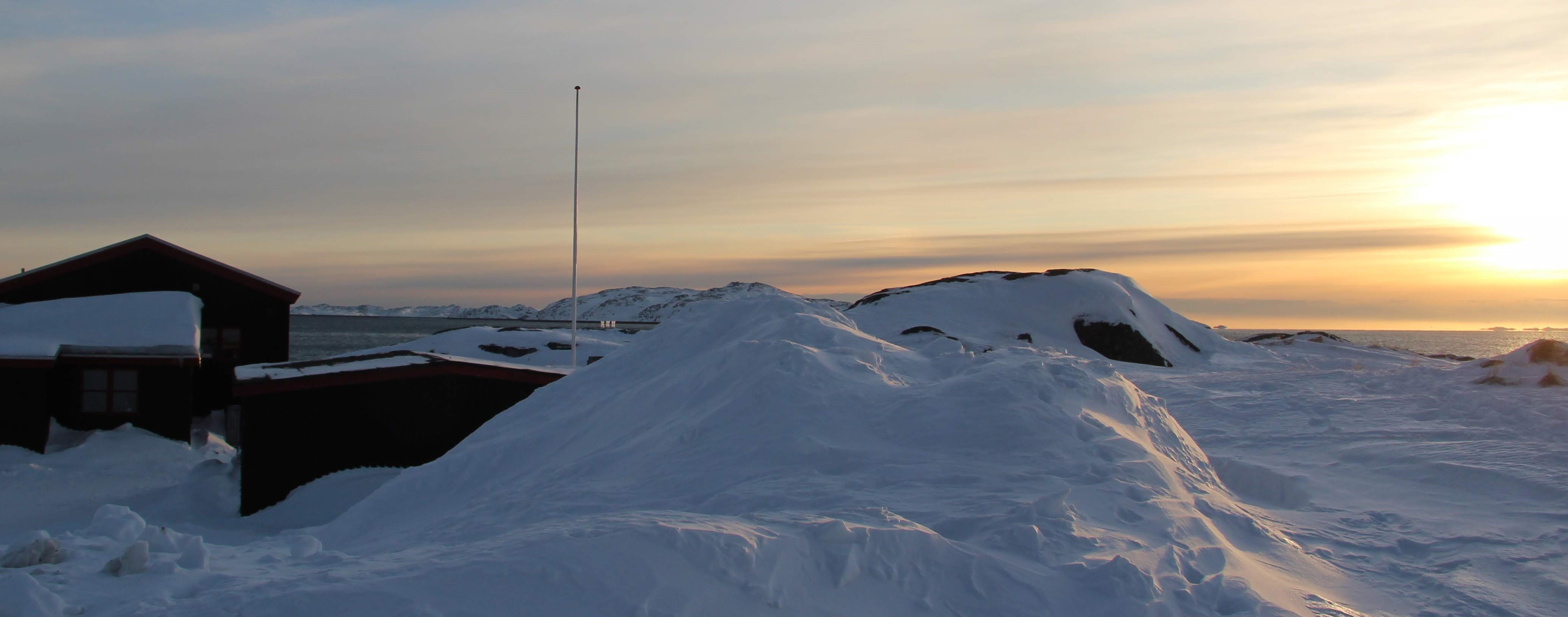 Billedet viser solnedgang over snedrive og bygning 